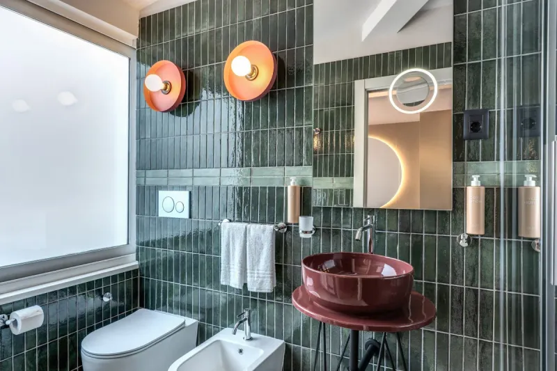 Junior Suite bathroom with green tiles, burgundy sink and bright window in modern setting in Rome - Barberini 16, BZAR hotels in Rome